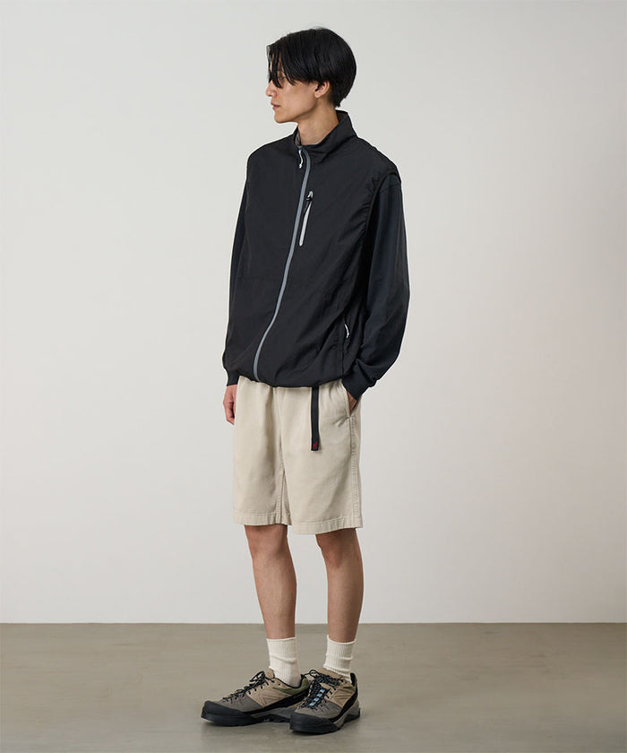 Model wearing sand pigment dye Gramicci G-Shorts and a black jacket on a light-tone background.