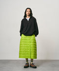 Model wearing a lime colored Gramicci G-Zero Primaloft Skirt and a black  jacket on a light-tone background.