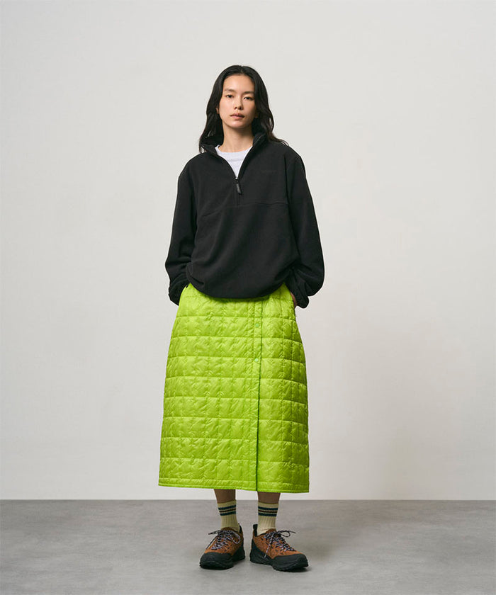 Model wearing a lime colored Gramicci G-Zero Primaloft Skirt and a black  jacket on a light-tone background.