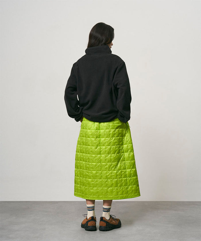 Model wearing a lime colored Gramicci G-Zero Primaloft Skirt and a black  jacket on a light-tone background.