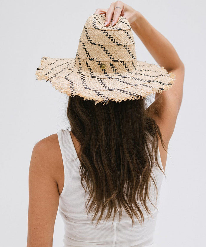 Woman wearing a natural colored straw hat with black patterns and a white top, posing against a plain background  #color_natural - black