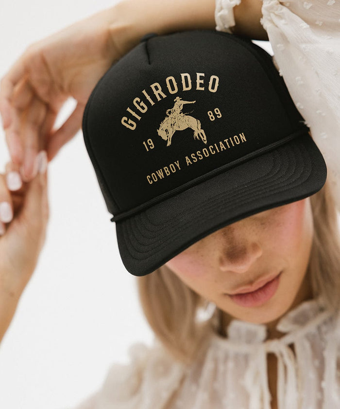 Person wearing a black cap with golden 'GIGIRODEO' text and logo against a plain background #color_black
