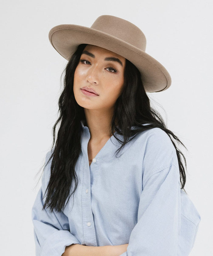 Woman wearing a taupe colored gambler hat and a blue shirt against a plain background #color_taupe