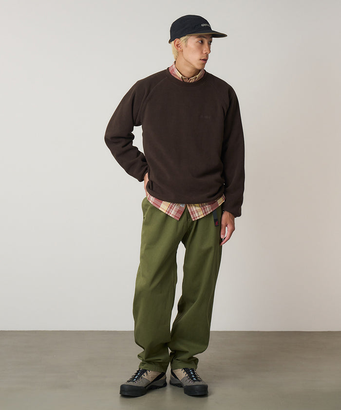 Model wearing olive Gramicci Pants and a brown sweatshirt on a light-tone background.