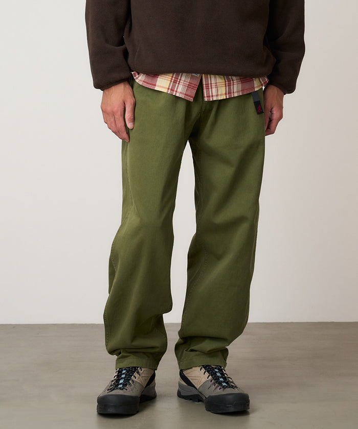 Model wearing olive Gramicci Pants and a brown sweatshirt on a light-tone background.