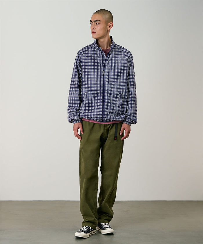 Model wearing olive Gramicci Pants and a plaid jacket on a light-tone background.