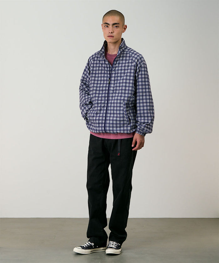 Model wearing black Gramicci Pants and a blue checkered jacket on a light-tone background.
