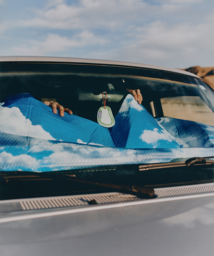 Photo of a car windshield with an Olive Gramicci & retaW Carabiner Car Tag air freshener hanging from rearssss-view mirror.