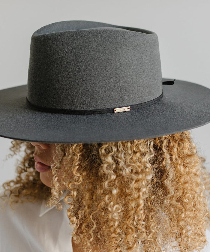Woman wearing a grey hat with a black grosgrain hat band facing sideways against a plain background #color_black