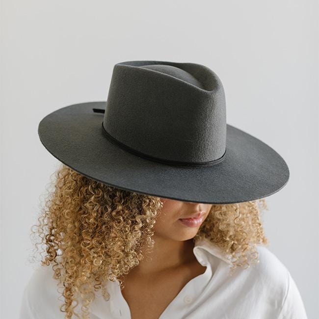 Woman wearing a grey hat with a black grosgrain hat band and a white shirt against a plain background #color_black