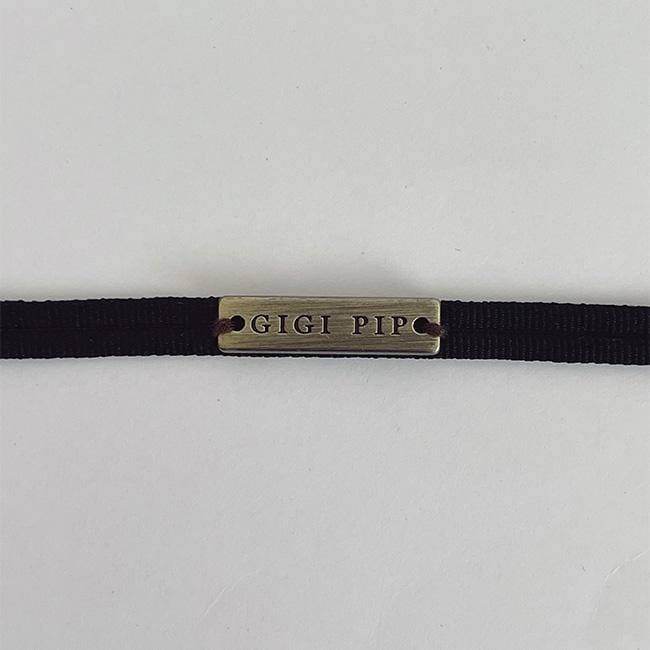 Close up image of a black grosgrain band with the brand label on a plain background #color_black
