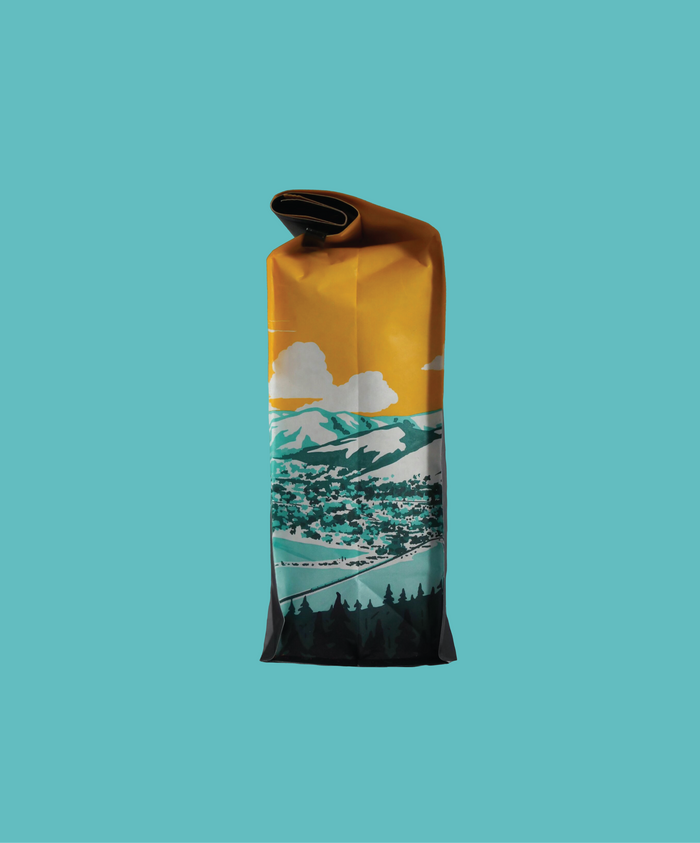 Yellow pouch with mountain graphics at bottom and a rolled top against a teal background