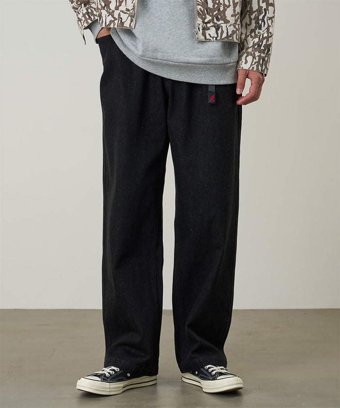 Model wearing black Gramicci Hemp Denim Pants and a camo jacket on a light-tone background.