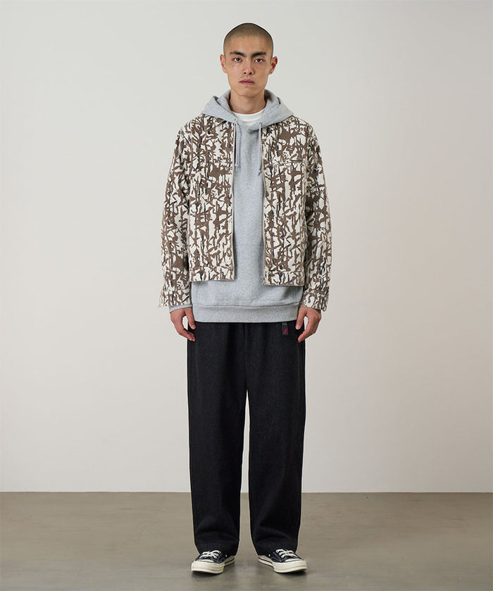 Model wearing black Gramicci Hemp Denim Pants and a camo jacket on a light-tone background.