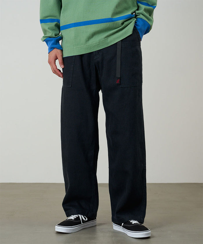 Model wearing carbon colored Gramicci Hemp Relaxed Pants and a green and blue striped shirt on a light-tone background.