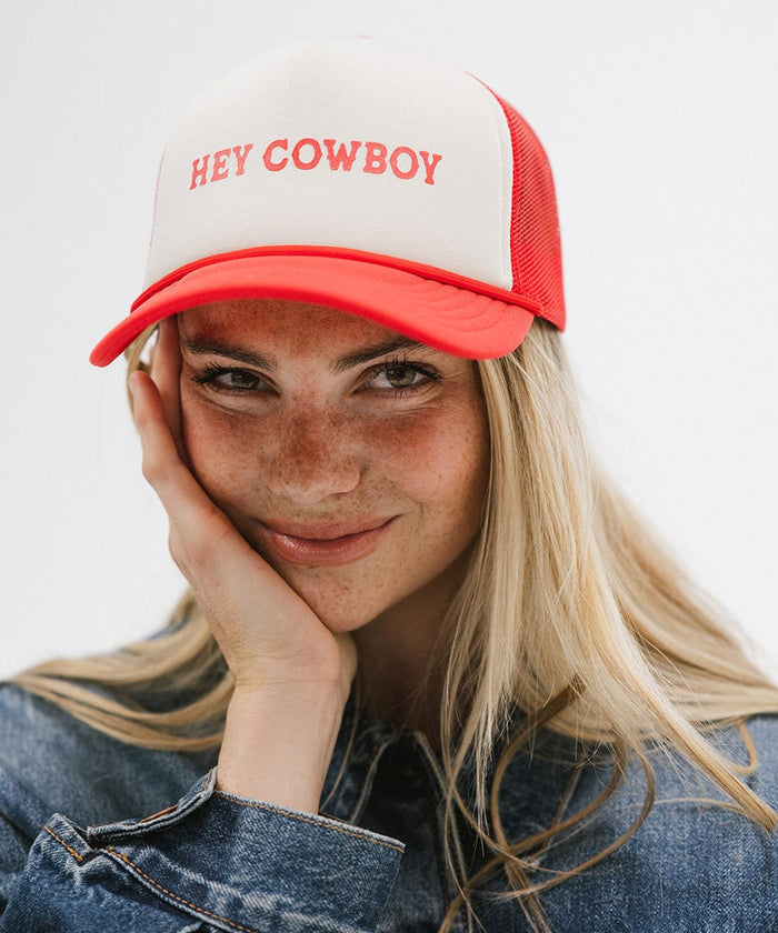 Woman wearing a cream and vintage red cap with 'Hey Cowboy' text and a denim shirt against a plain background  #color_cream - vintage red