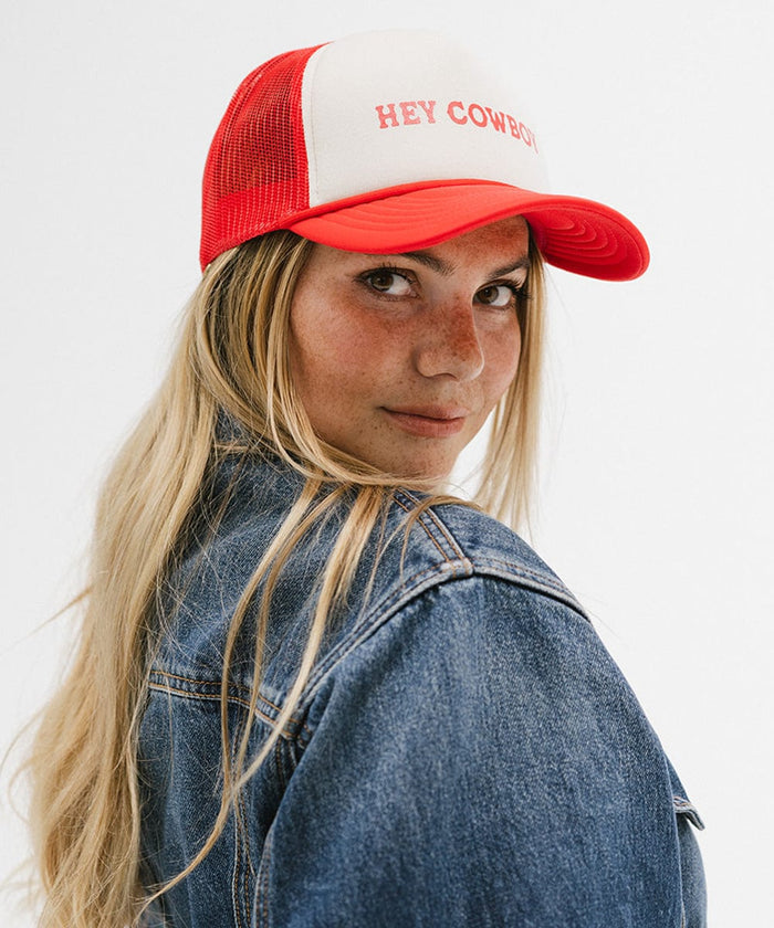 Woman wearing a cream and vintage red cap with 'Hey Cowboy' text and a denim shirt, posing sideways against a plain background  #color_cream - vintage red