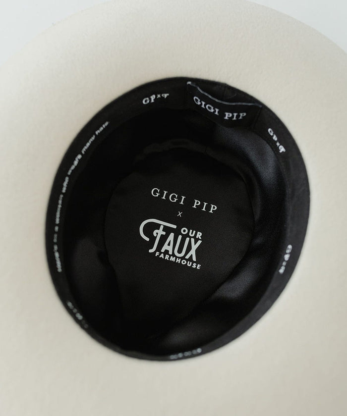 The inside of an off white felt fedora hat with the brand label on a plain background #color_off white