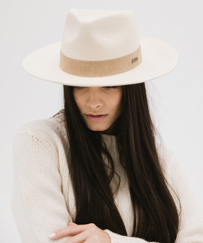 Woman wearing an off white felt fedora hat with a band and a white sweater, posing against a plain background  #color_off white