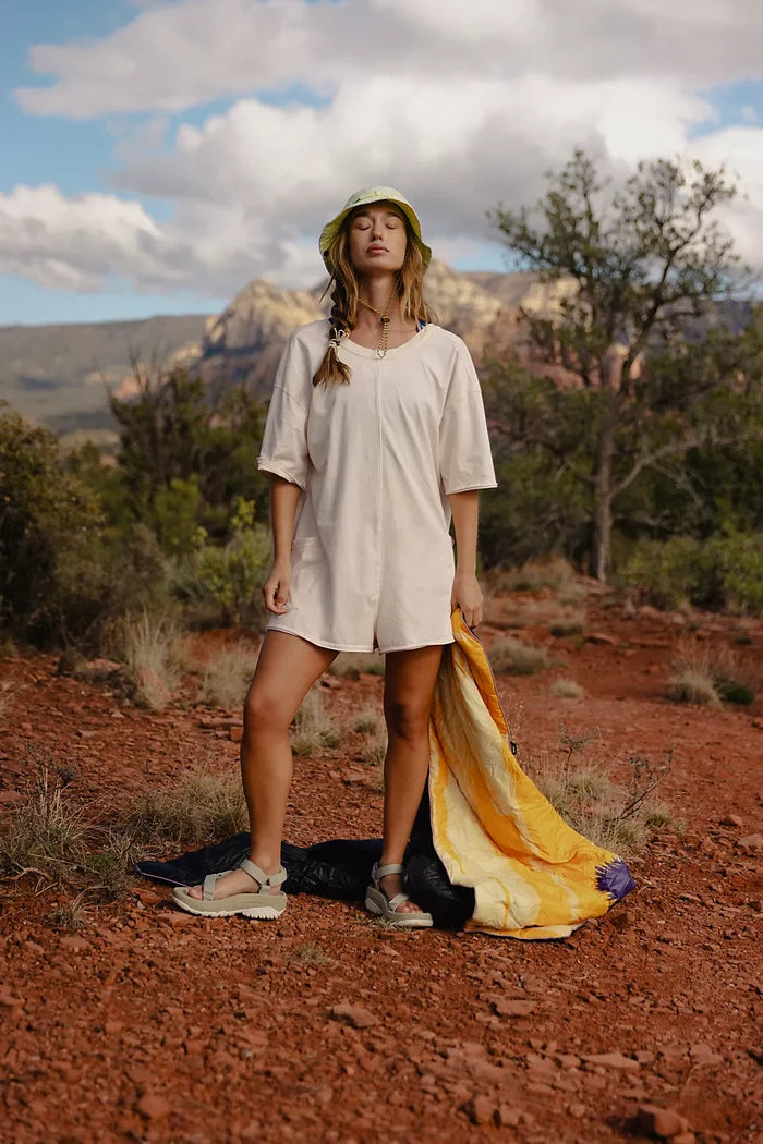 Woman wearing Free People Hot Shot Tee Romper Coddy in bleached clay standing in outdoors