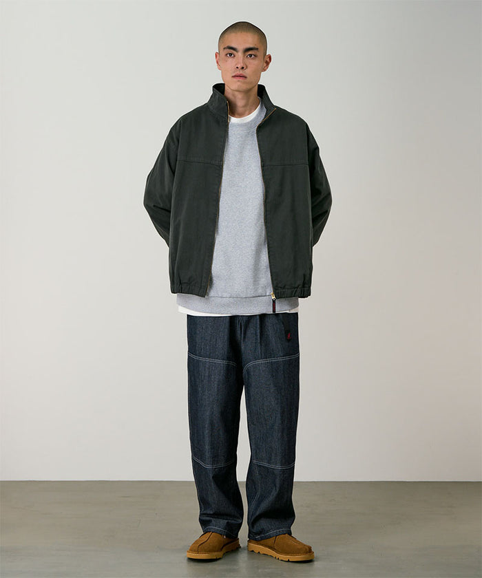 Model wearing the Gramicci Japanese Chambray Double Knee pant in navy and a dark green jacket on a light tone background.
