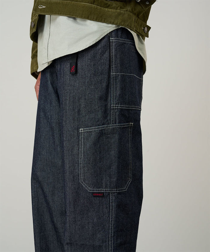 Model wearing navy Japanese Chambray Rock Slide Pants and a moss green jacket on a light-tone background.