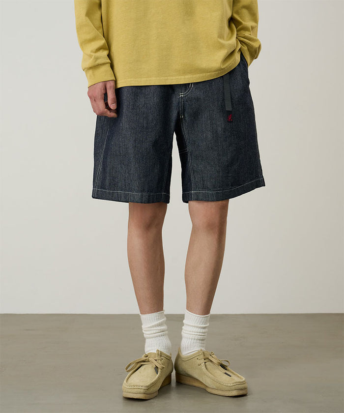 Model wearing navy Gramicci Japanese Chambray Shorts and a yellow shirt on a light-tone background.