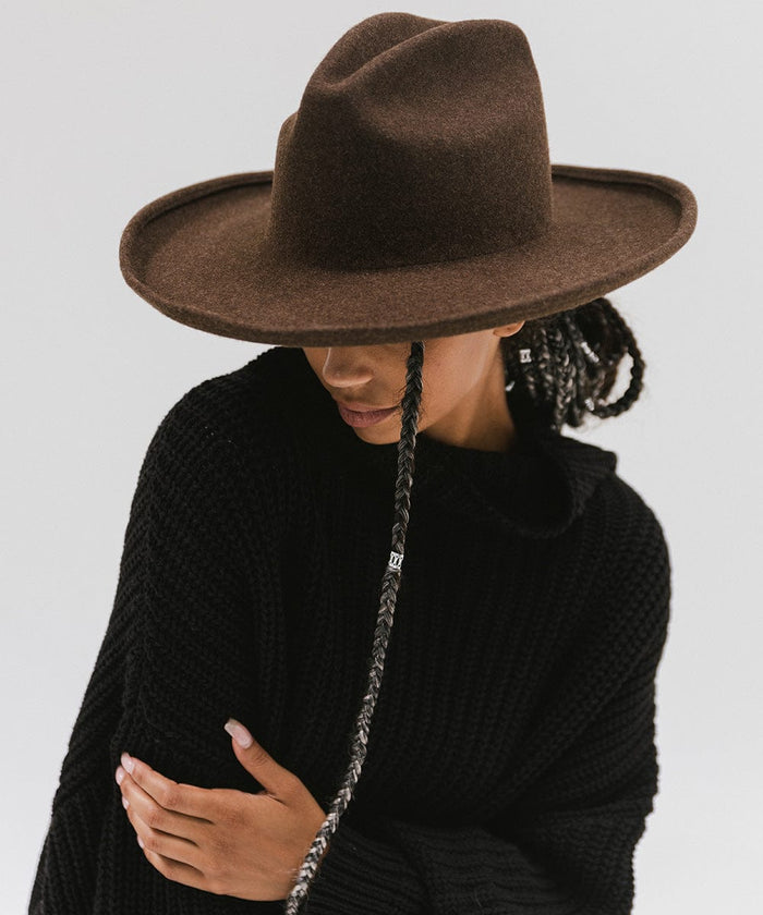 Woman wearing a mix brown colored western hat with a pencil brim and a tall crown, and a black sweater against a plain background  #color_mix brown