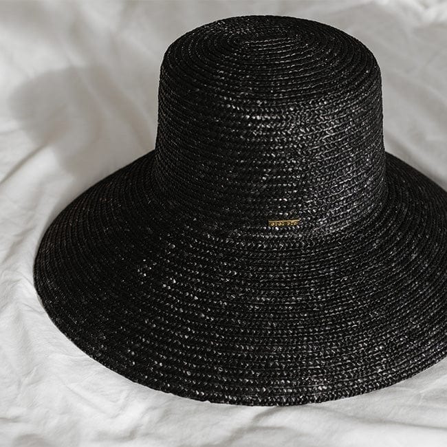 A black straw boater hat with a wide brim against a plain background #color_black