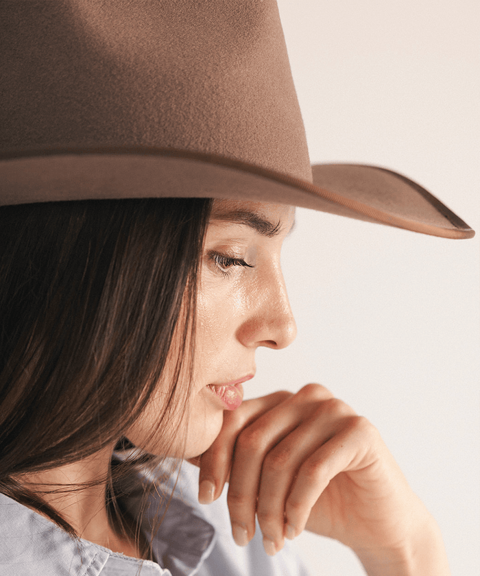 Woman wearing a brown felt hat on a white background #color_brown