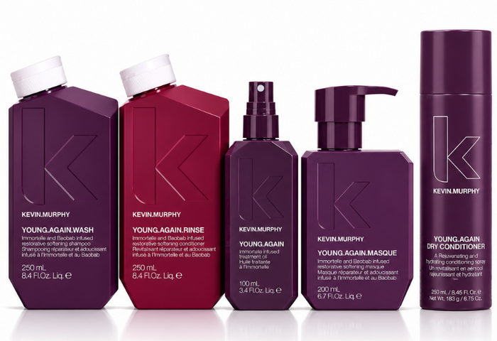 Six Kevin Murphy Young Again haircare products in a row on a white background, including wash, rinse, spray, masque, and dry conditioner bottles in deep purple and burgundy tones.