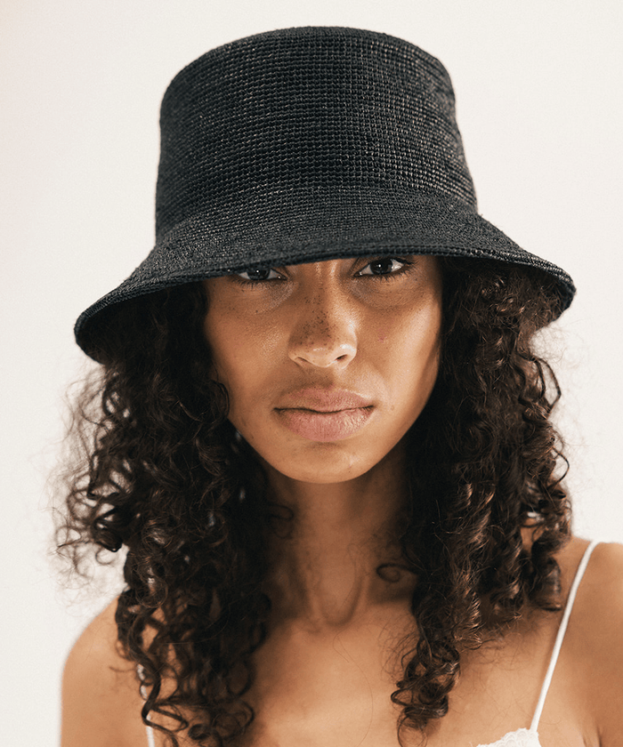 Woman wearing a black bucket hat against a white background #color_black