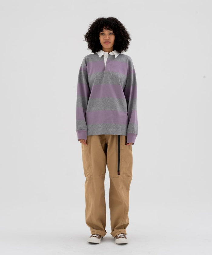 Model wearing beige Gramicci Voyager Pants and a lavender and grey stripped Gramicci Langdon Rugby  Long-Sleeve shirt on a light-tone background.