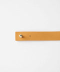 A camel colored leather band with pin on a plain background #color_camel