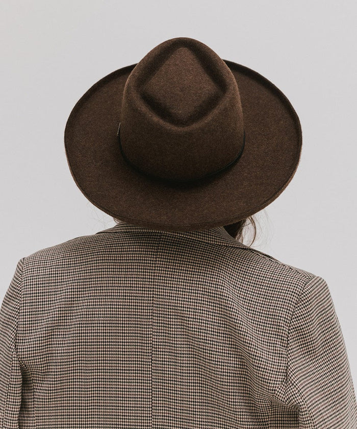Person wearing a mix brown Lennon pencil brim fedora hat with a hat band and a coat against a plain background #color_mix brown