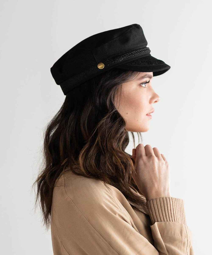 Woman wearing a black lieutenant  cap and a beige jacket, facing sideways against a plain background #color_black
