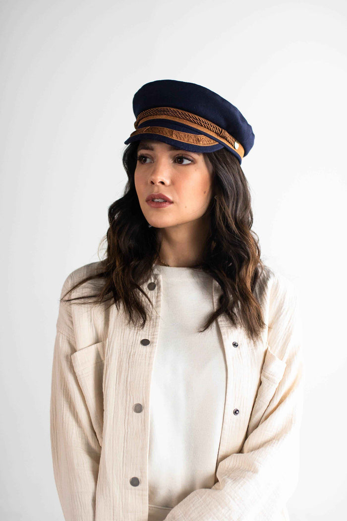 Woman wearing a navy and gold colored lieutenant cap and a white t-shirt inside a cream shirt against a plain background #color_navy