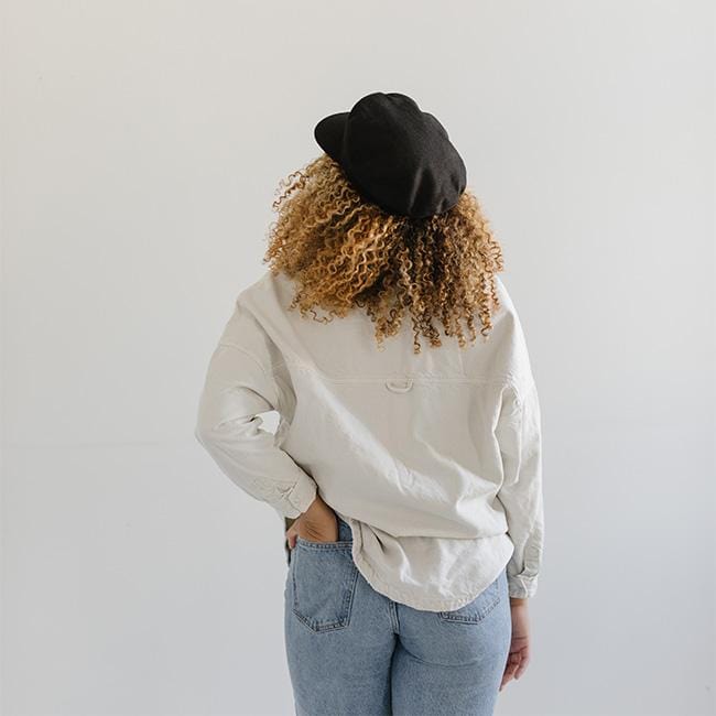 Woman wearing a black cap, a white shirt and blue jeans against a plain background #color_black