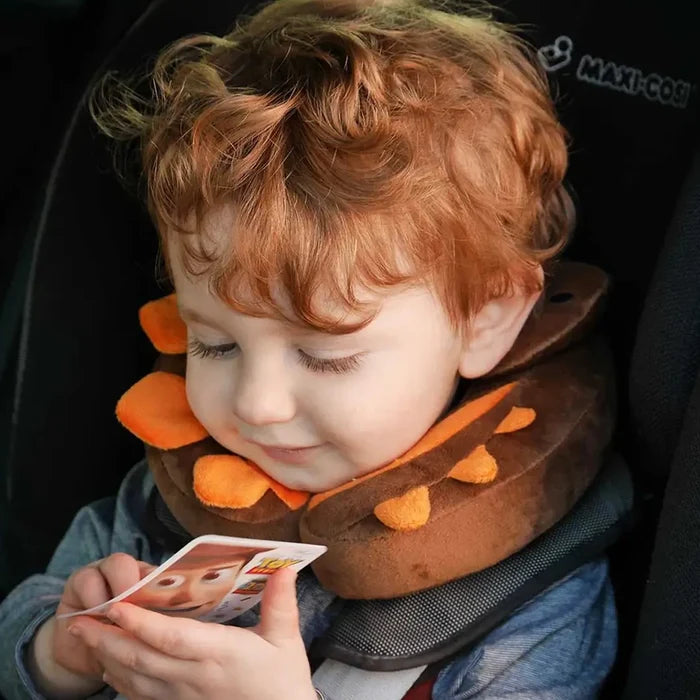 Toddler wearing a dinosaur design Littlelife kids neck pillow whilst strapped in to a car seat