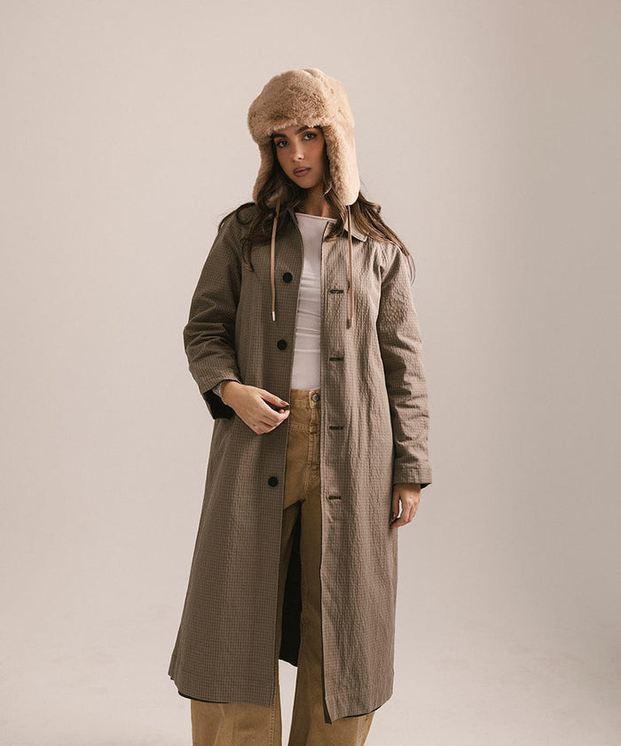Woman wearing a long coat and fur hat on a plain background #color_tan