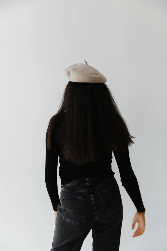 Woman wearing a taupe beret, black t-shirt and jeans against a plain background  #color_taupe