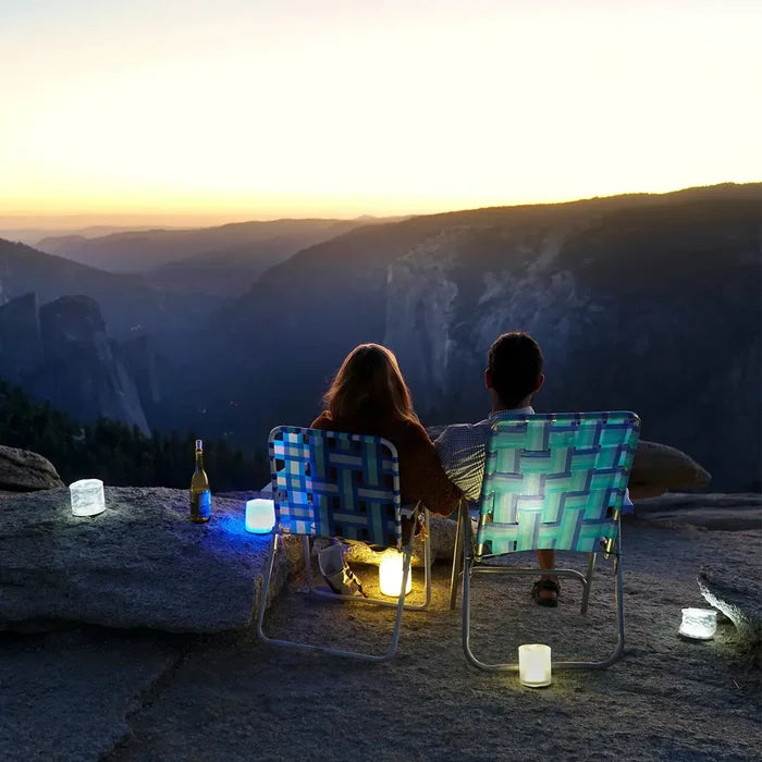 Couple looking out over the mountains at sunset with Luci Color Inflatable Solar Lanterns littered around them