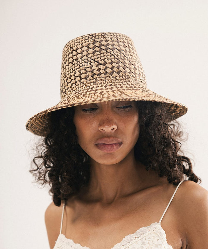 Woman wearing a woven bucket hat against a plain background #color_natural brown