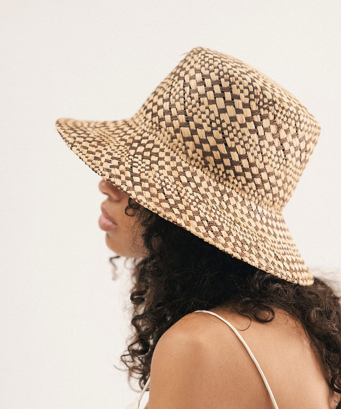 Woman wearing a woven bucket hat against a plain background #color_natural brown