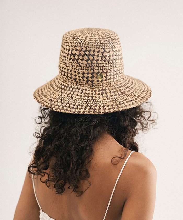 Woman wearing a woven bucket hat against a plain background #color_natural brown