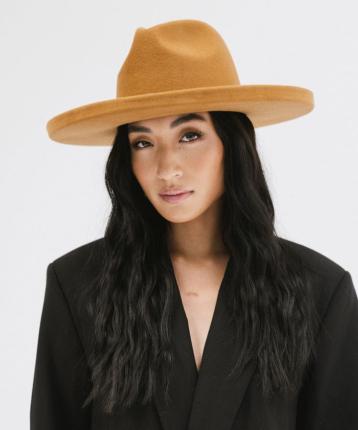 Woman wearing a cinnamon colored  pencil brim felt fedora hat and a black blazer against a white background #color_cinnamon