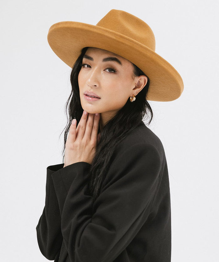 Woman wearing a cinnamon colored  pencil brim felt fedora hat and a black blazer, posing against a white background #color_cinnamon