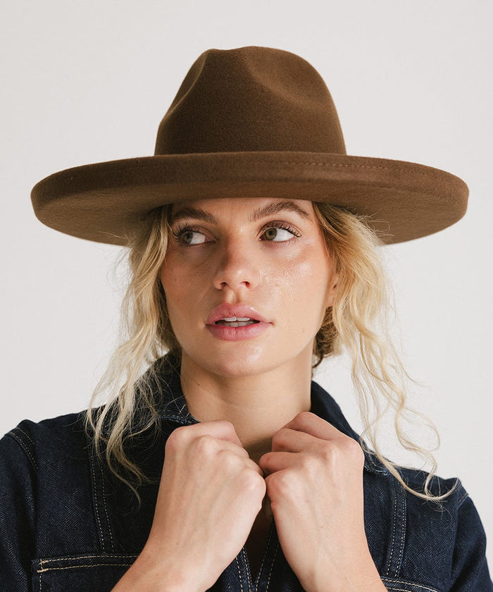 Woman wearing a chocolate colored pencil brim fedora hat and a denim shirt against a plain background #color_chocolate