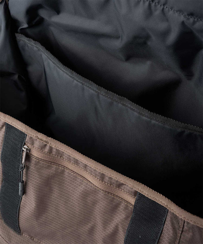 Close-up of a brown and black Gramicci Messenger Bag interior on a light tone background.
