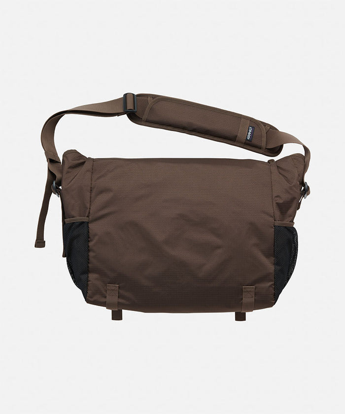 Back view of a brown and black Gramicci Messenger Bag on a light tone background.